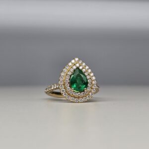 Pear shaped emerald engagement ring with double diamond halo in 18k yellow gold on a diamond pave shank